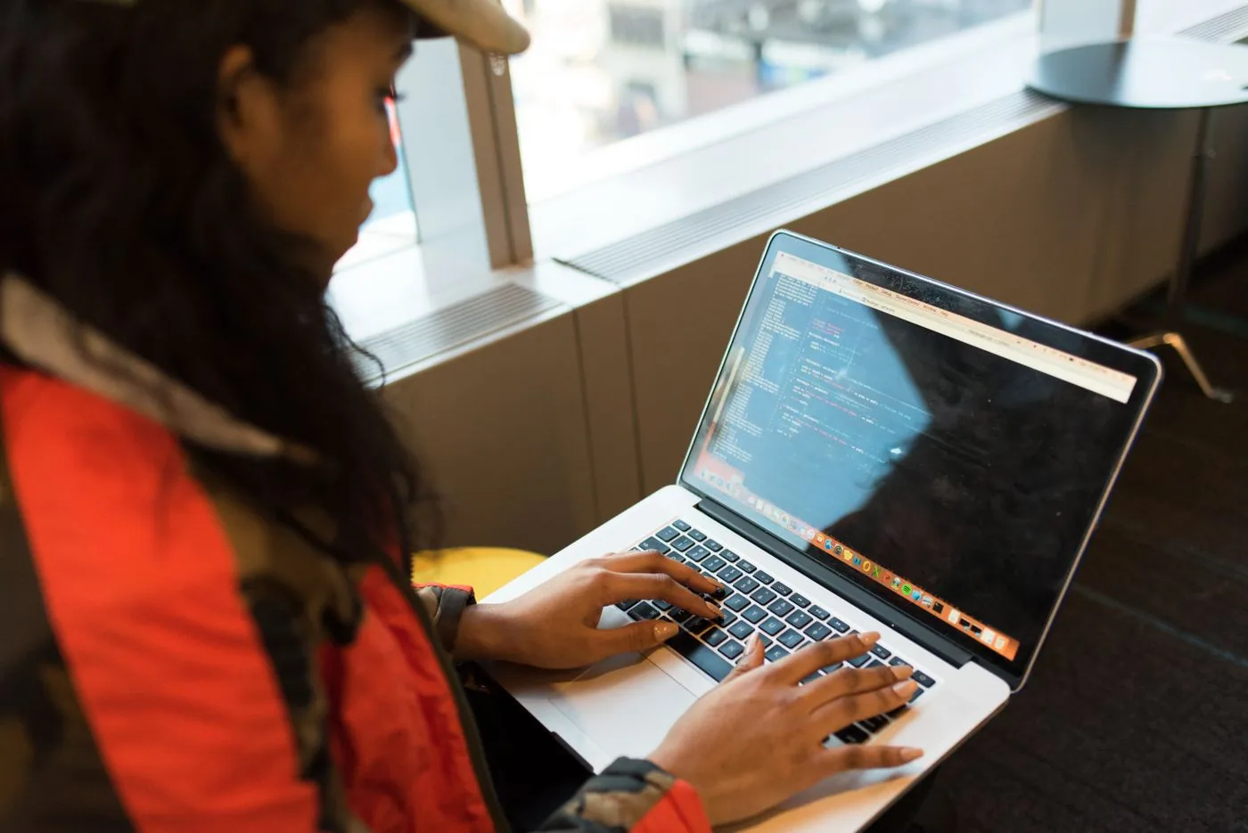A developer concentrating on work at a laptop by a window