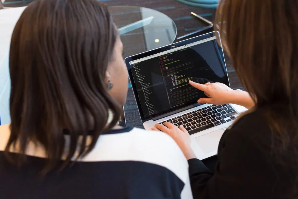 Two developers reviewing code together on a laptop