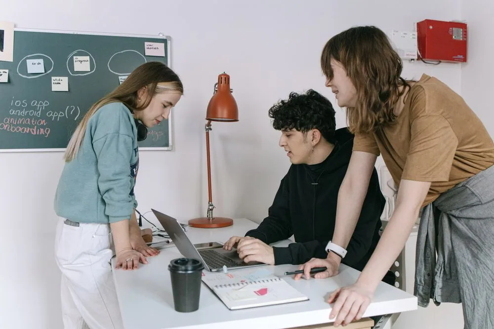 Three colleagues discussing a project around a laptop