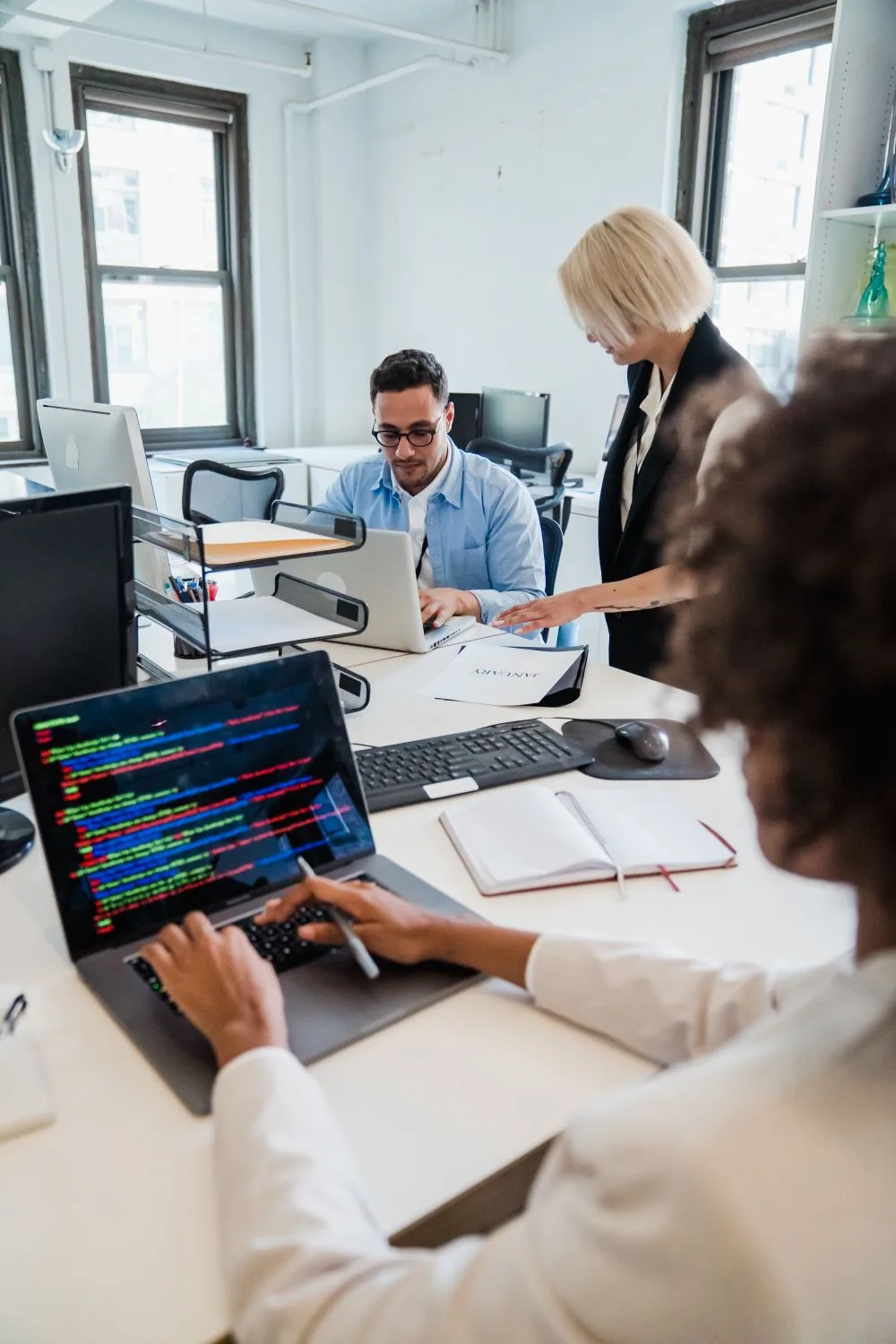 Software developers collaborating around computers in a shared office