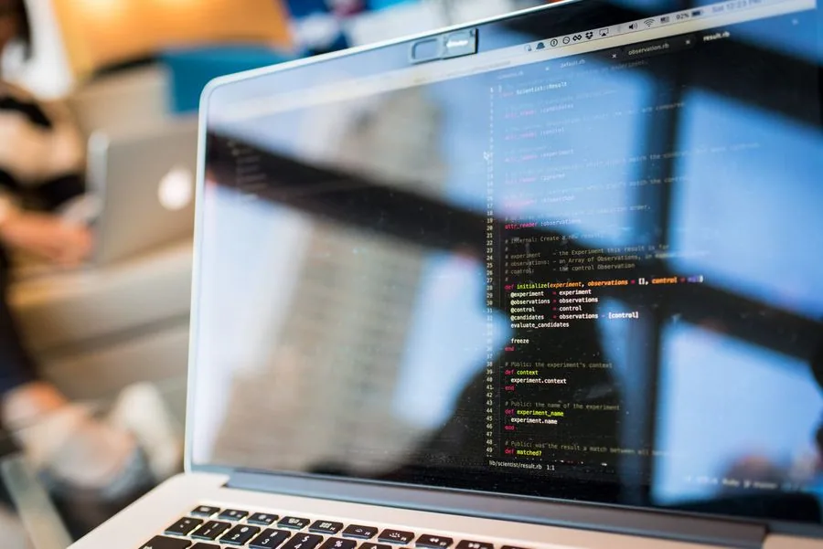 Code and reflections on the screen of an open laptop