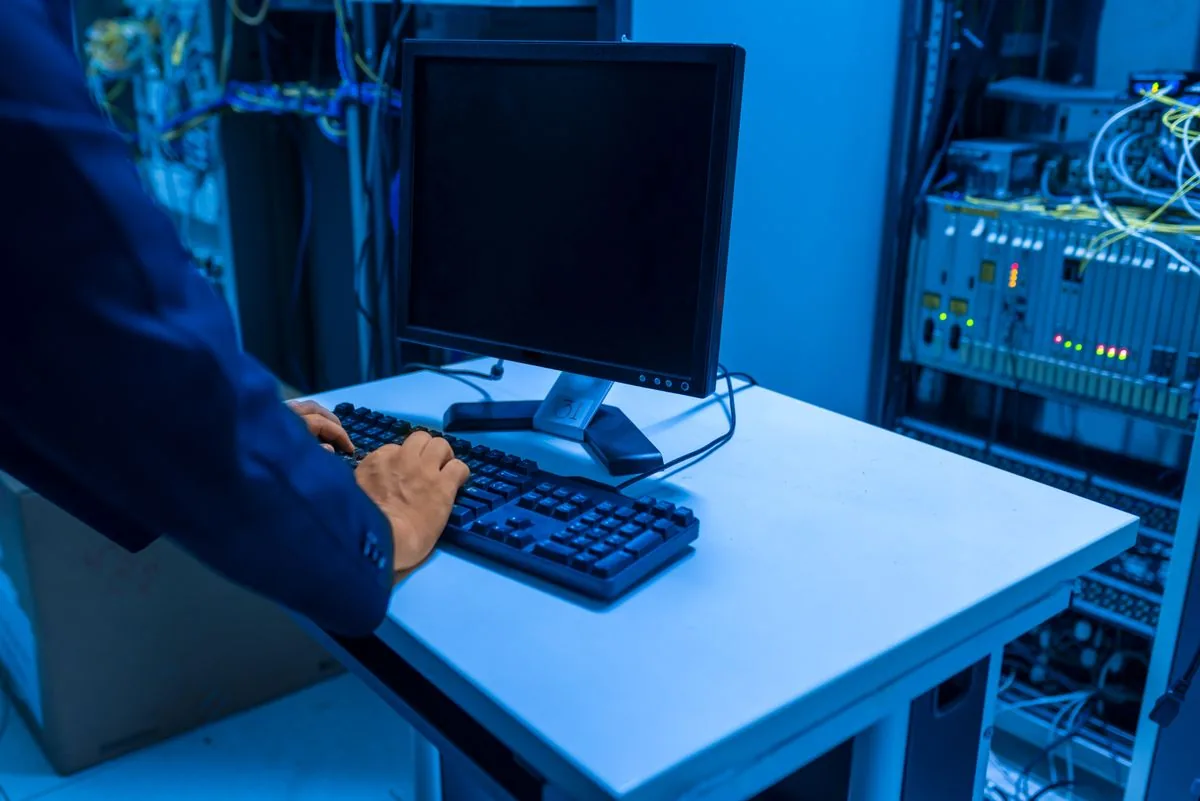 An IT professional operating a workstation beside network racks