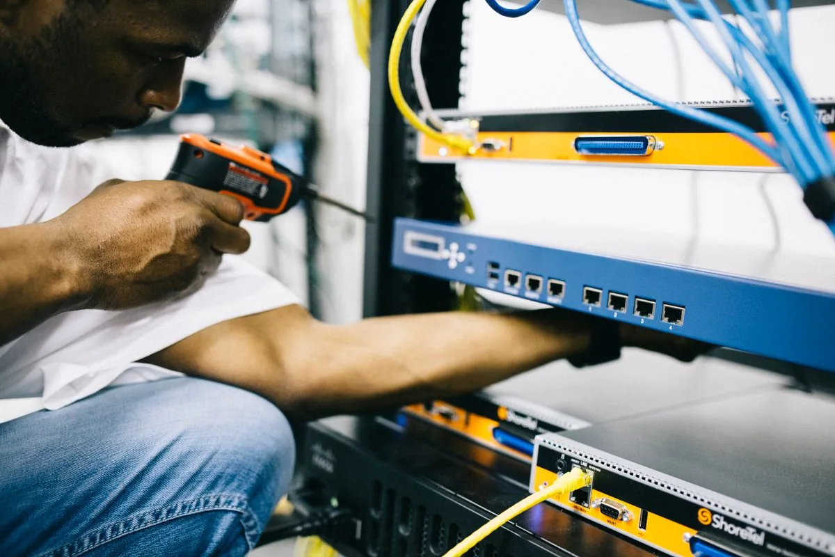 A field engineer maintaining network equipment and cabling
